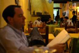 Robert peruses the menu while the wait staff relax ~ customer service in Rome is far different from home